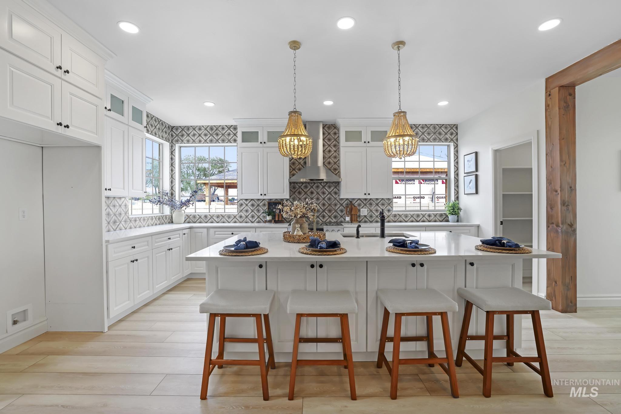 866 Quartz Road Kimberly, ID 83341 - Photo 11 of 48 Spacious kitchen featuring white shaker cabinetry, patterned tile backsplash, light wood-finish flooring, recessed lighting, and a substantial island with seating