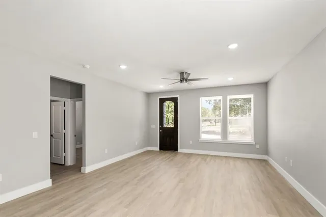 an empty room with wooden floor and windows