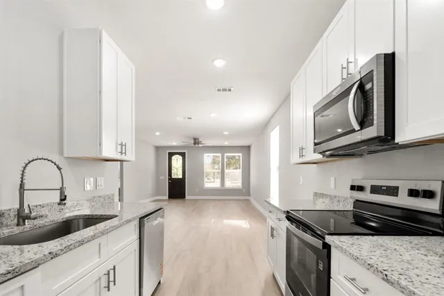 a kitchen with granite countertop a sink a stove and cabinets