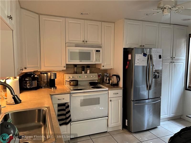 a kitchen with stainless steel appliances a refrigerator a stove a sink and white cabinets