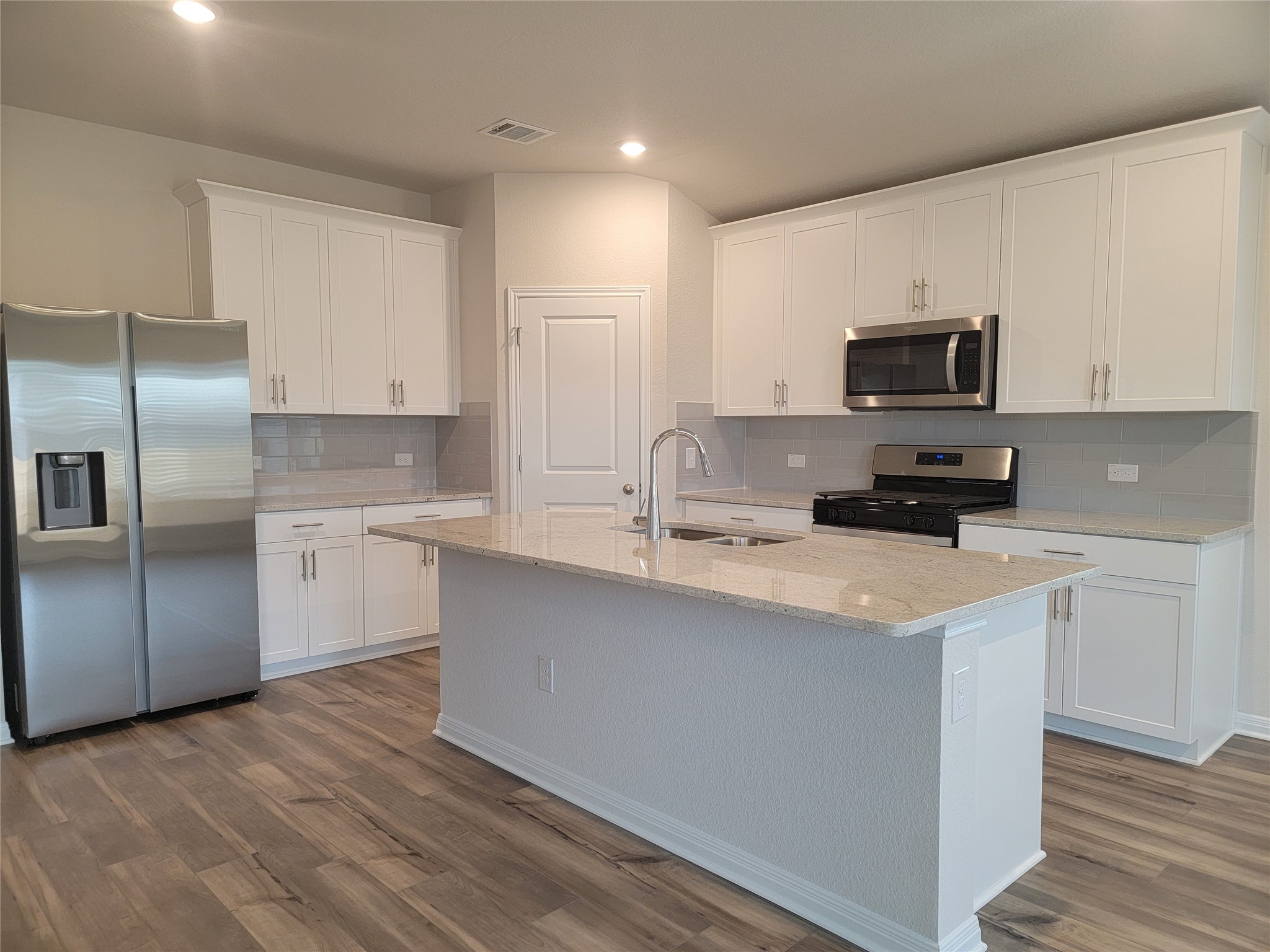 14317 Bryce Lane Manor, TX 78653 - Photo 14 of 26 a kitchen with stainless steel appliances a sink a stove a microwave a refrigerator a sink and white cabinets