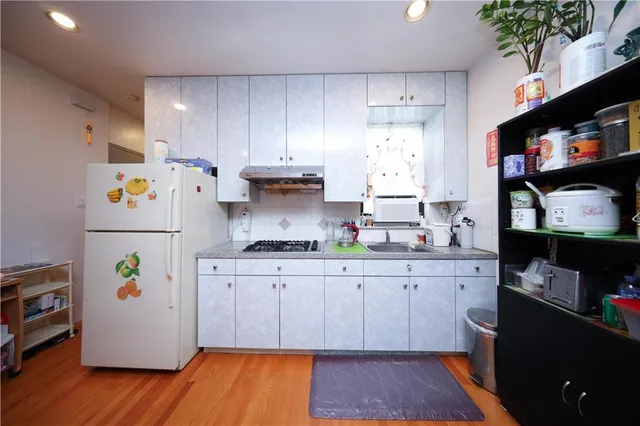 a kitchen with stainless steel appliances a stove a refrigerator a sink and wooden floor