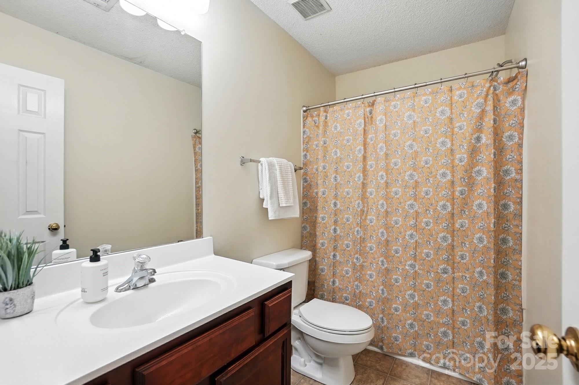8130 Rudolph Road Charlotte, NC 28216 - Photo 15 of 36 a bathroom with a sink a toilet and shower curtain