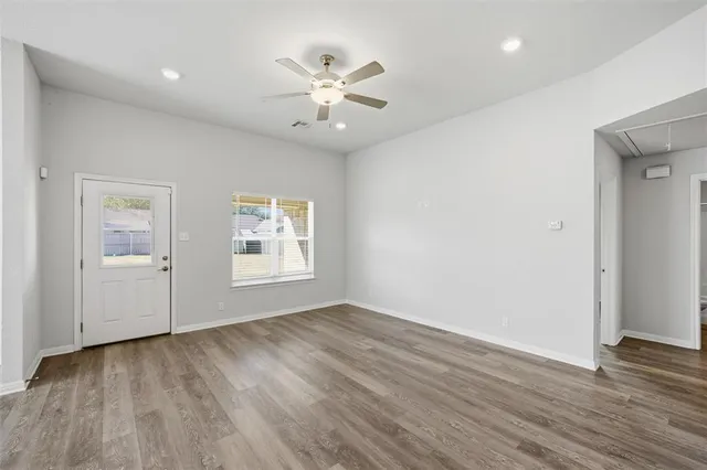 a view of an empty room with wooden floor and a window
