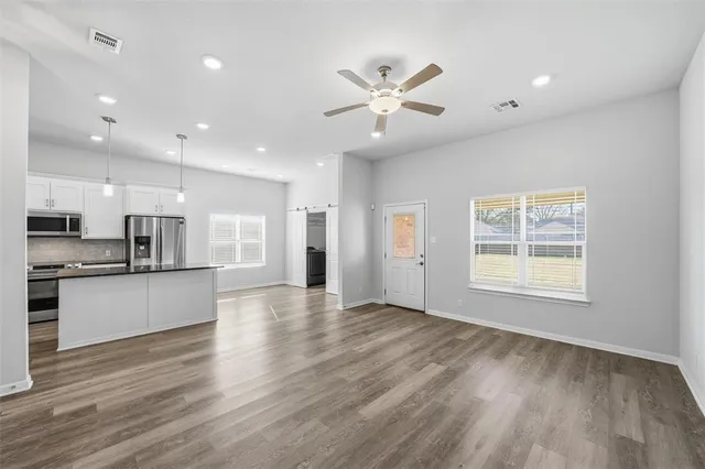 a view of an empty room with wooden floor and a window