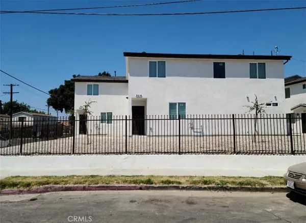 a view of a white house with wooden fence