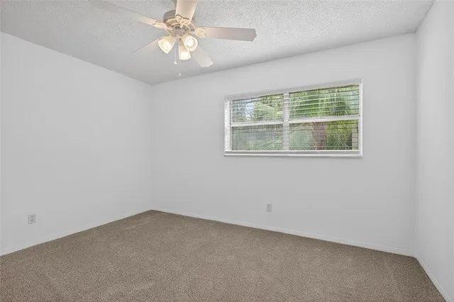 an empty room with a window and a fan