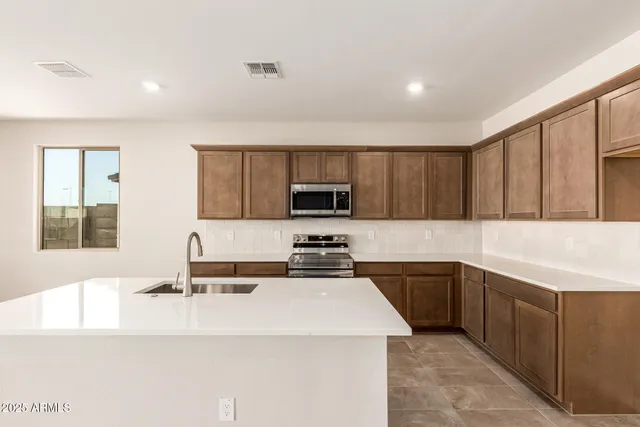 a kitchen with stainless steel appliances a sink a stove a microwave a sink a refrigerator and cabinets