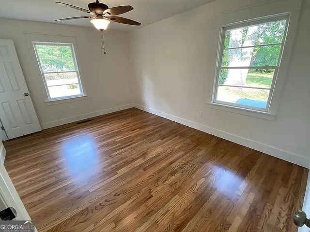 a view of an empty room with wooden floor and a window