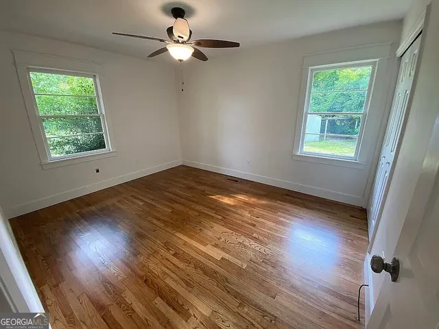 a view of empty room with wooden floor and fan