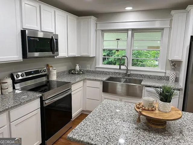 a kitchen with stainless steel appliances granite countertop a sink a stove and a microwave