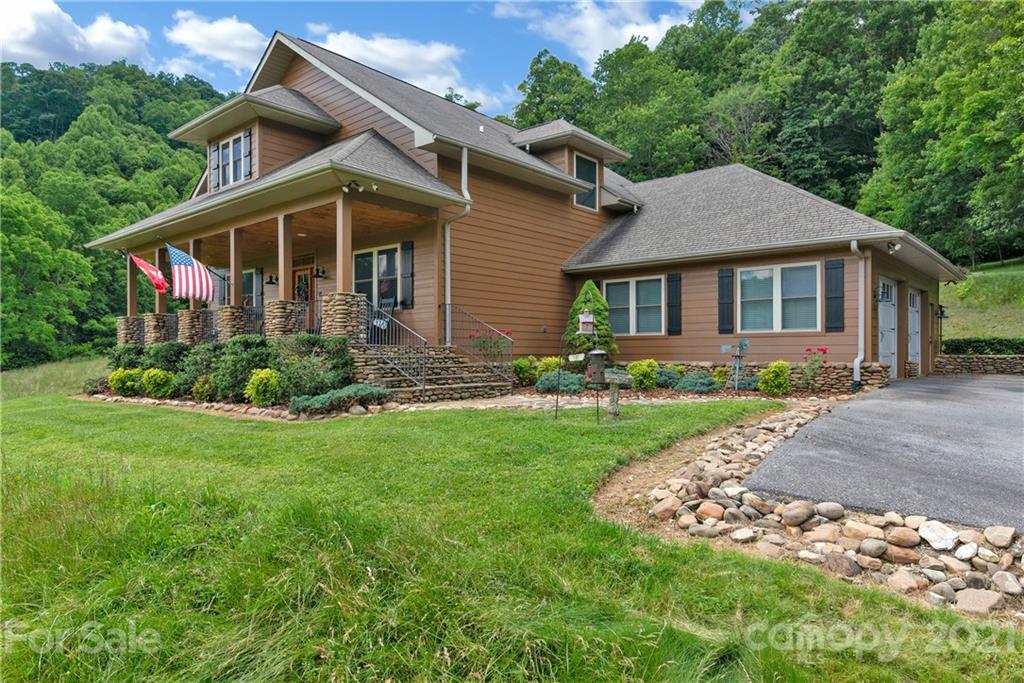 253 Benitez Way Clyde, NC 28721 - Photo 3 of 40 a front view of a house with a garden and plants