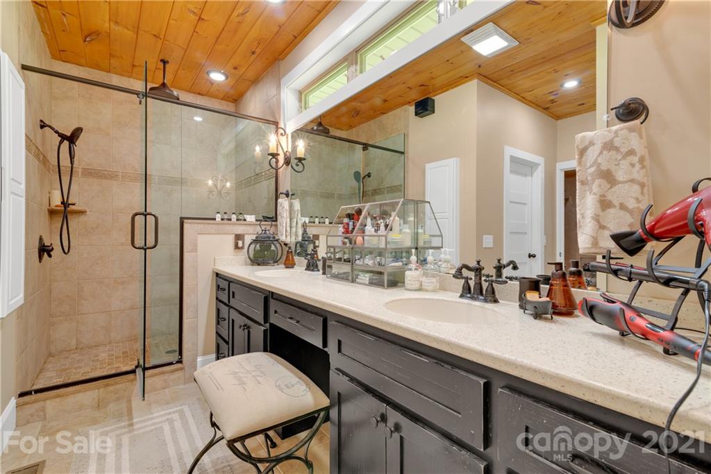 253 Benitez Way Clyde, NC 28721 - Photo 23 of 40 a bathroom with a double vanity sink a mirror and a shower