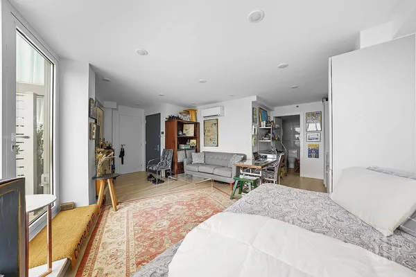 a living room with stainless steel appliances furniture a rug and a kitchen view