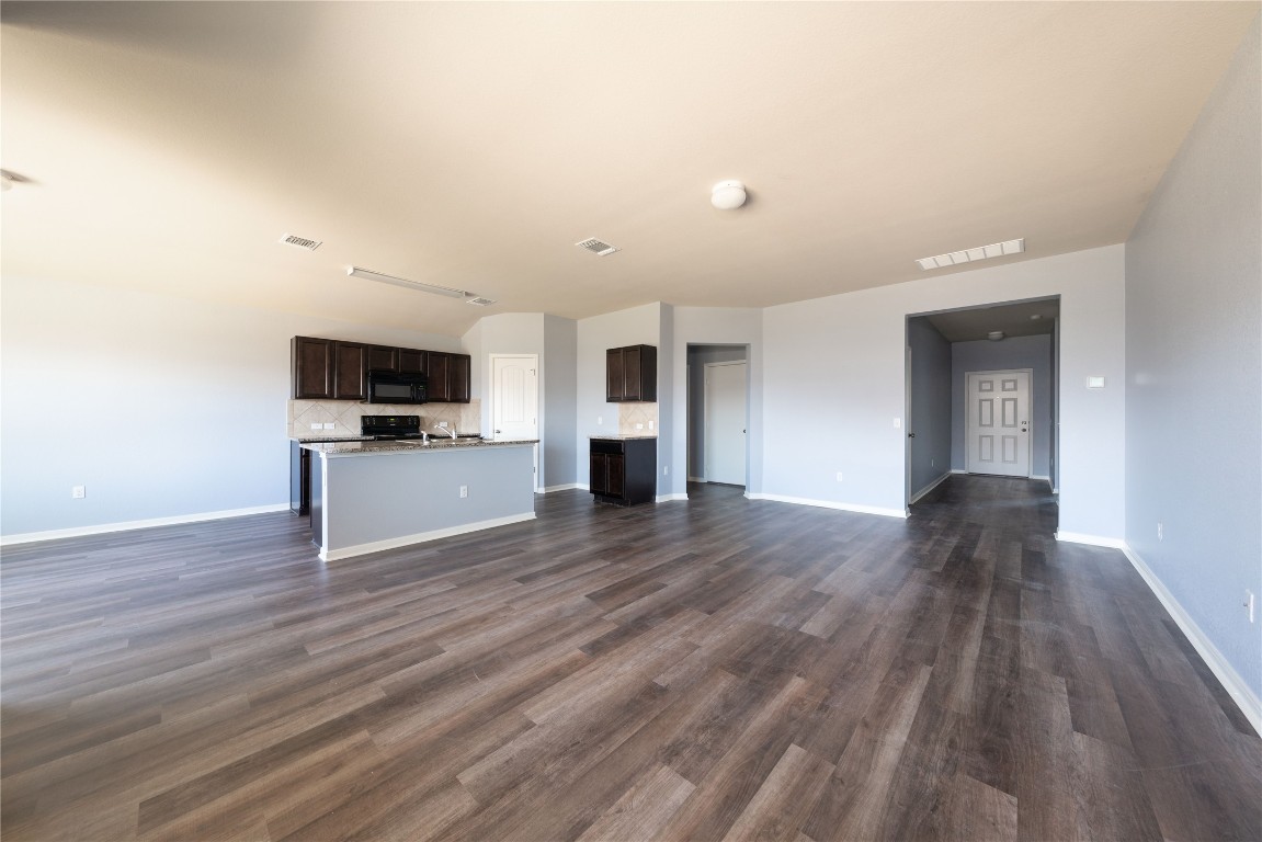 414 Pentire Way Hutto, TX 78634 - Photo 10 of 26 a view of empty room with wooden floor and kitchen