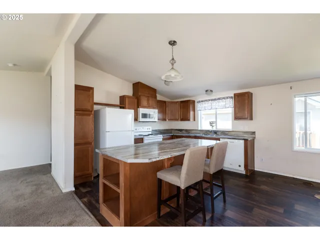 a kitchen with stainless steel appliances granite countertop a sink dishwasher and a refrigerator with wooden floor