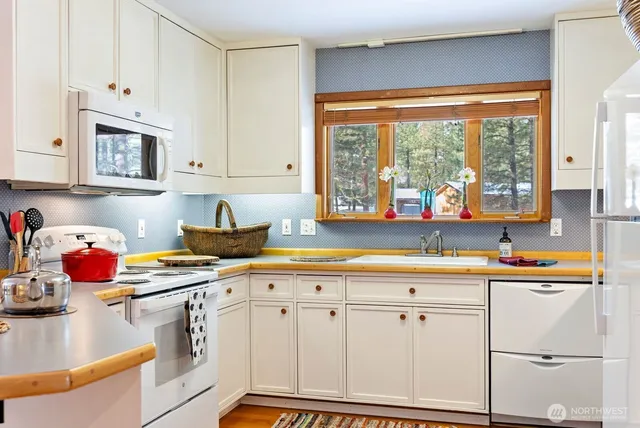 a kitchen with stainless steel appliances granite countertop a stove a refrigerator and a dining table with wooden cabinet