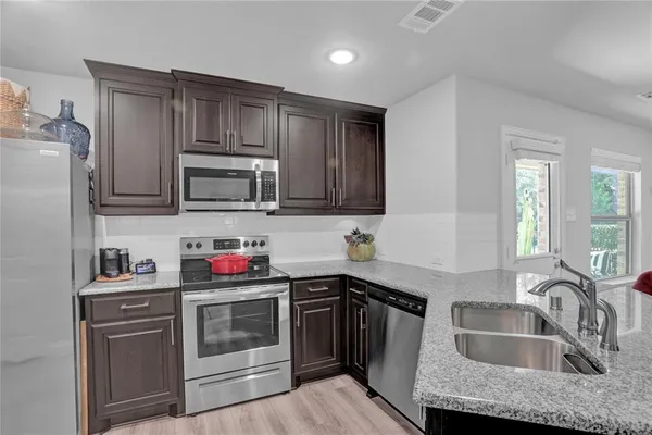 a kitchen with granite countertop a sink stove and cabinets