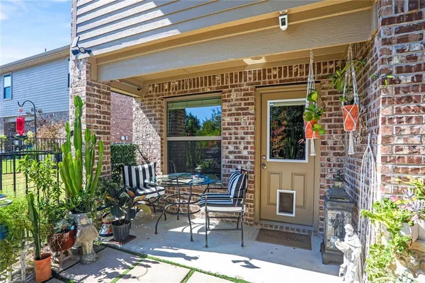 a view of a patio with table and chairs potted plants and floor to ceiling window and potted plants