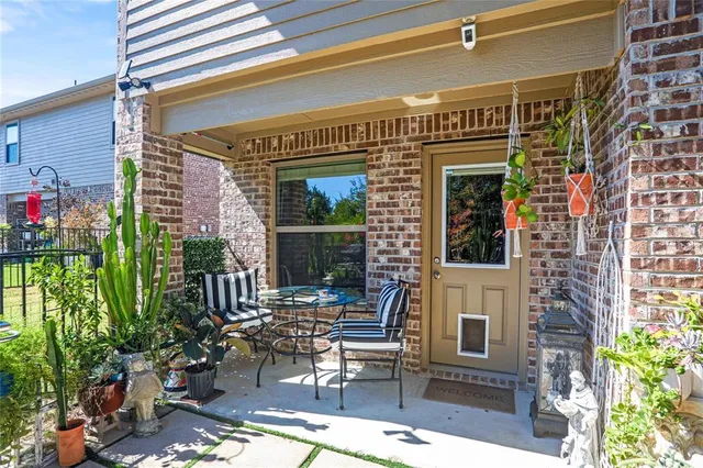 a view of a patio with table and chairs potted plants and floor to ceiling window and potted plants