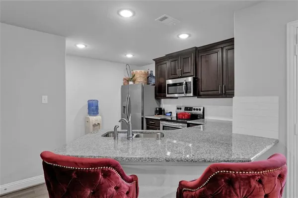 a living room with stainless steel appliances kitchen island granite countertop a couch and a flat screen tv