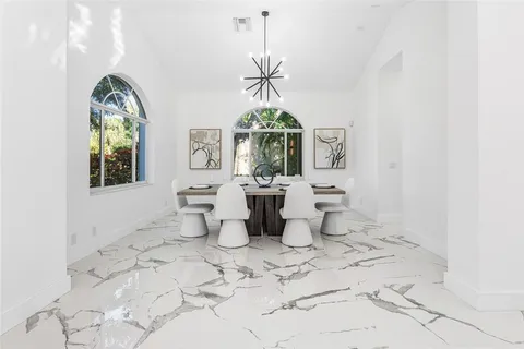 a dining room with wooden floor a chandelier a wooden table and chairs