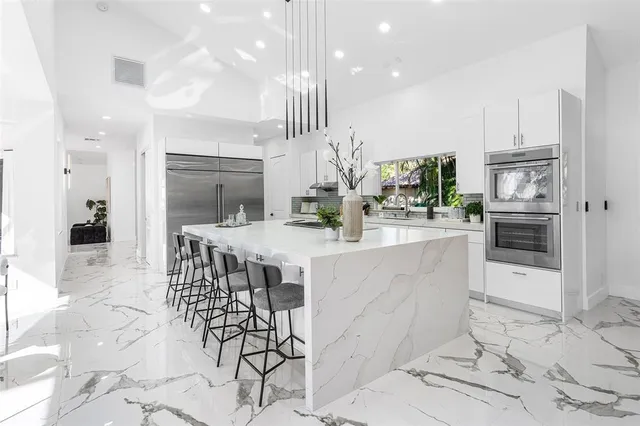 a kitchen with stainless steel appliances kitchen island granite countertop a refrigerator and a stove top oven