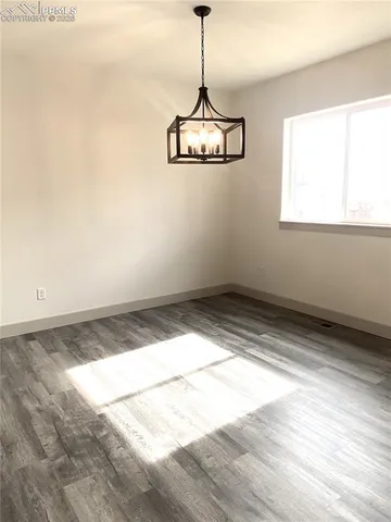 an empty room with wooden floor fireplace and windows