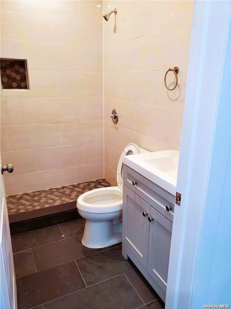 3043 Fulton Street Brooklyn, NY 11208 - Photo 14 of 14 a bathroom with a granite countertop toilet a sink and a mirror