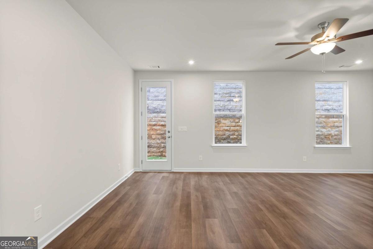 706 Smokey Quartz Way Kennesaw, GA 30144 - Photo 14 of 35 an empty room with wooden floor chandelier fan and windows