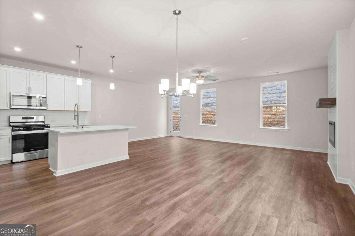 706 Smokey Quartz Way Kennesaw, GA 30144 - Photo 6 of 35 a view of a kitchen with kitchen island a sink wooden floor and stainless steel appliances
