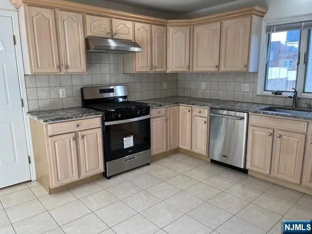 a kitchen with granite countertop white cabinets and stainless steel appliances
