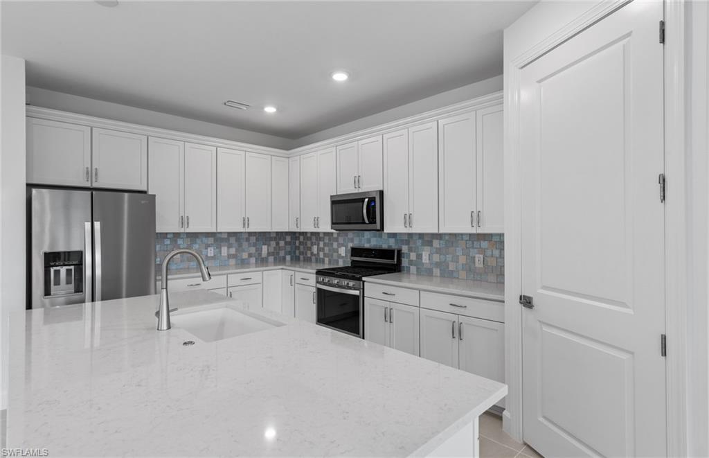 42544 Adirondack Drive Punta Gorda, FL 33982 - Photo 13 of 29 a kitchen with white cabinets and stainless steel appliances