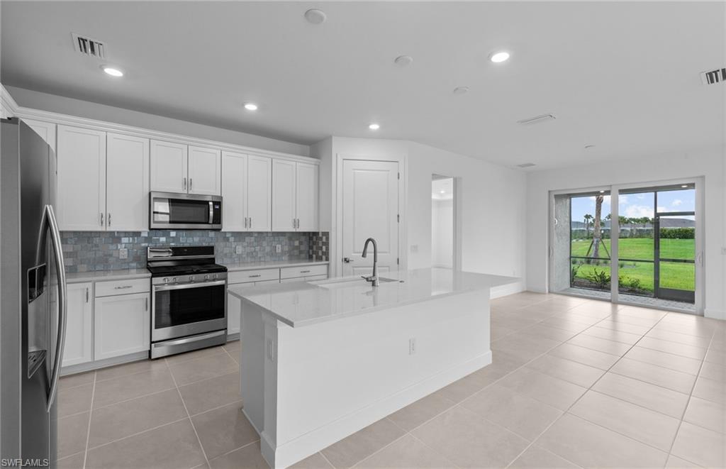 42544 Adirondack Drive Punta Gorda, FL 33982 - Photo 16 of 29 a large kitchen with kitchen island a large counter top space a sink stainless steel appliances and cabinets