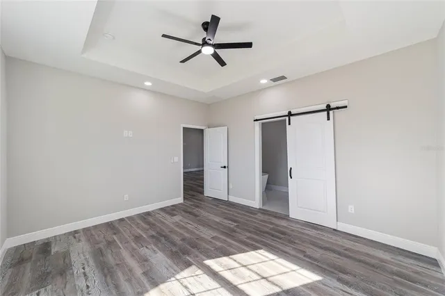 a view of empty room with wooden floor and fan
