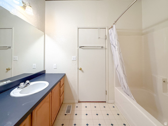 141 South 100 East Emery, UT 84522 - Photo 12 of 17 Bathroom featuring a white bathtub with shower, an extended vanity with a dark countertop and integrated sink, wood-finish cabinetry, and a large wall-mounted mirror