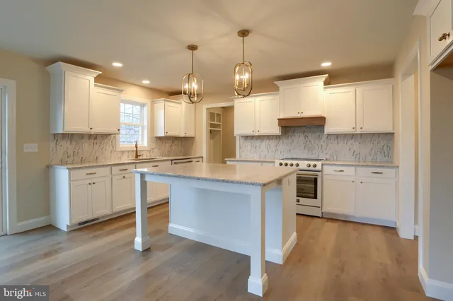 a large kitchen with granite countertop a white cabinets stainless steel appliances and a center island