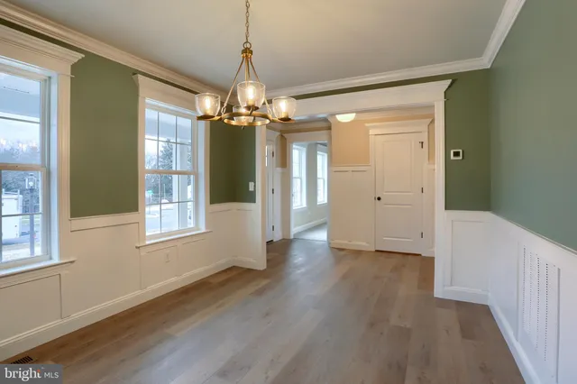 a view of a room with wooden floor chandelier and windows