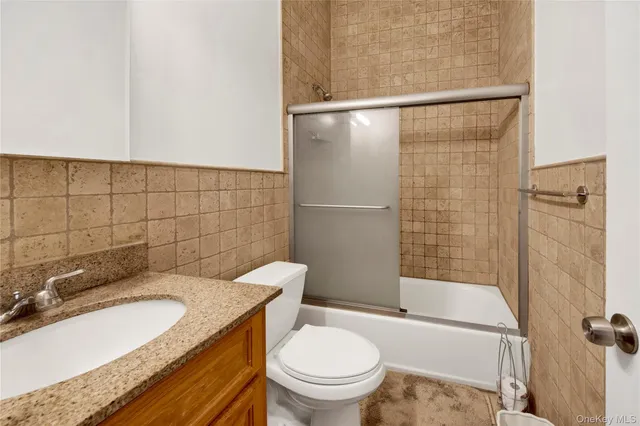 a bathroom with a granite countertop bathtub shower sink mirror and toilet