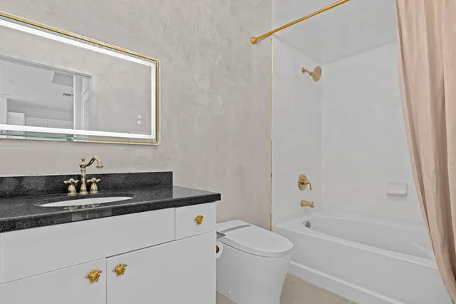 a bathroom with a granite countertop sink a toilet and shower