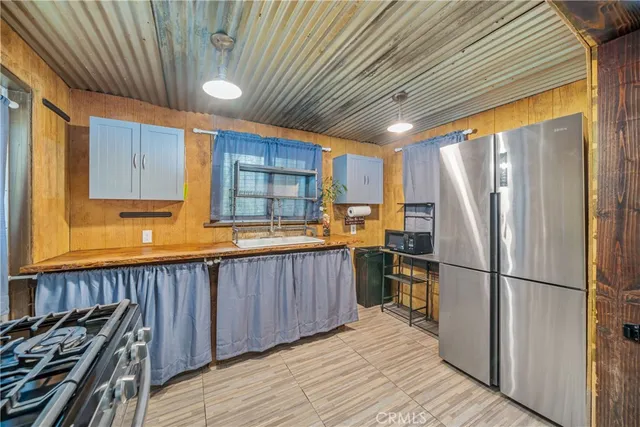 a kitchen with stainless steel appliances granite countertop a refrigerator a sink dishwasher a stove and white countertops with wooden floor