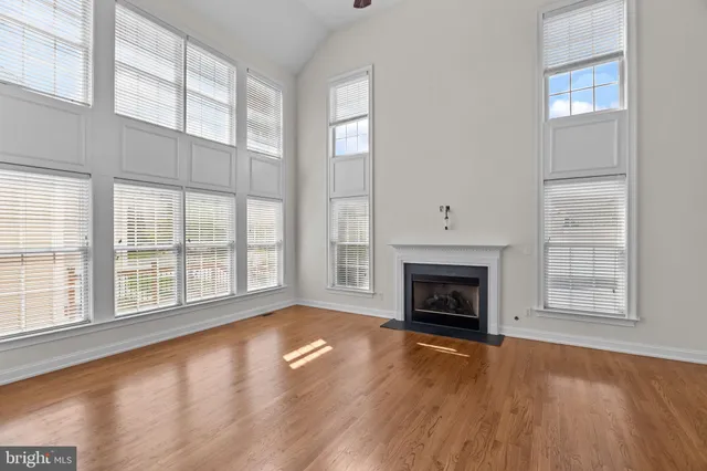 wooden floor fireplace and windows in an empty room