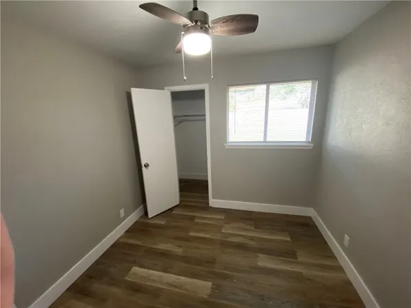 an empty room with wooden floor fan and window