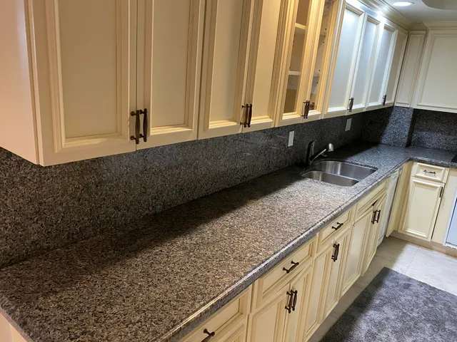 a kitchen with granite countertop white cabinets and sink