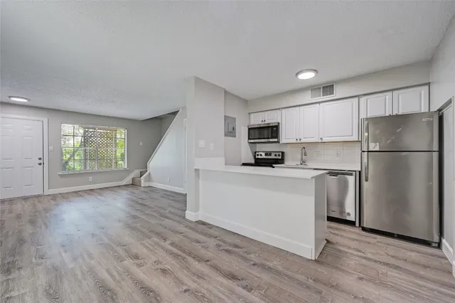 a kitchen with a refrigerator a stove top oven and white wooden cabinets