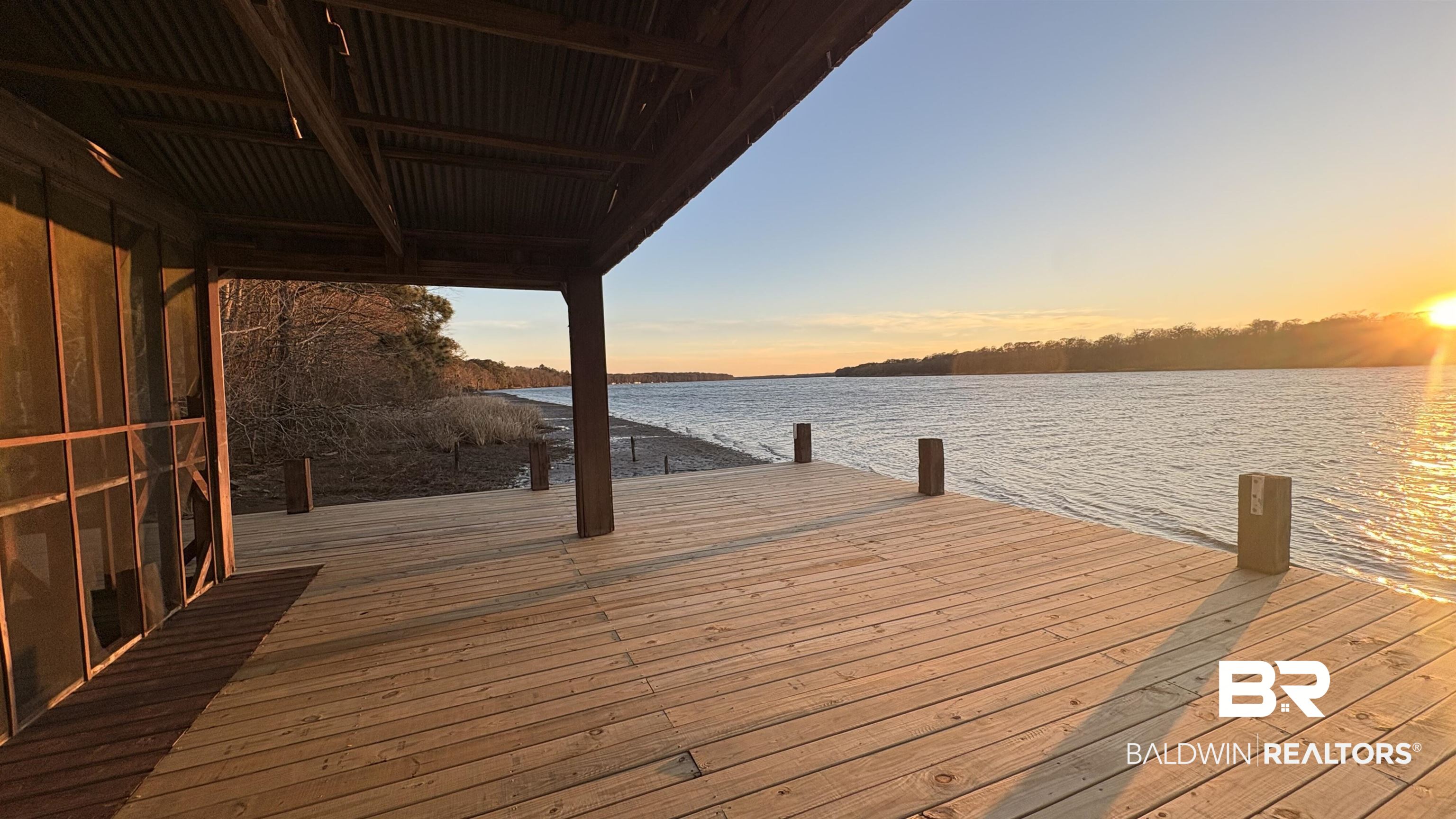 8008 Patricks Landing Road Bay Minette, AL 36507 - Photo 31 of 33 Expansive wood deck with water frontage, featuring a covered patio with a corrugated metal roof and exposed wood beams