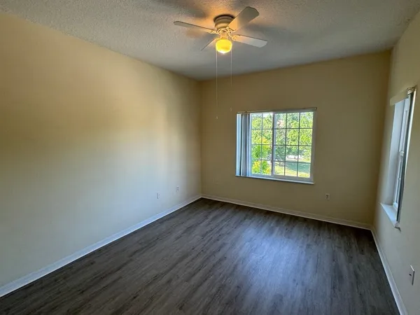 a view of an empty room with window and wooden floor
