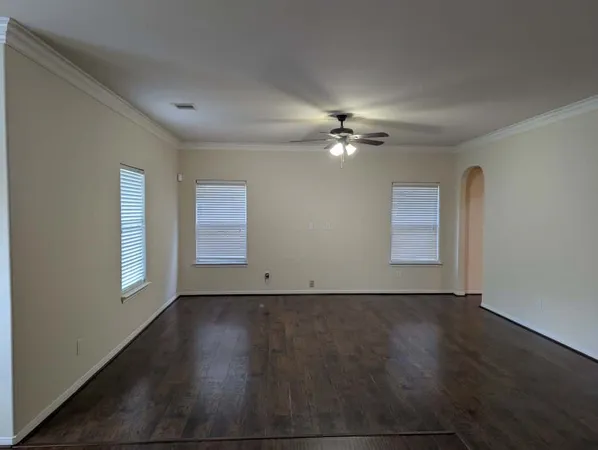 an empty room with wooden floor chandelier fan and windows