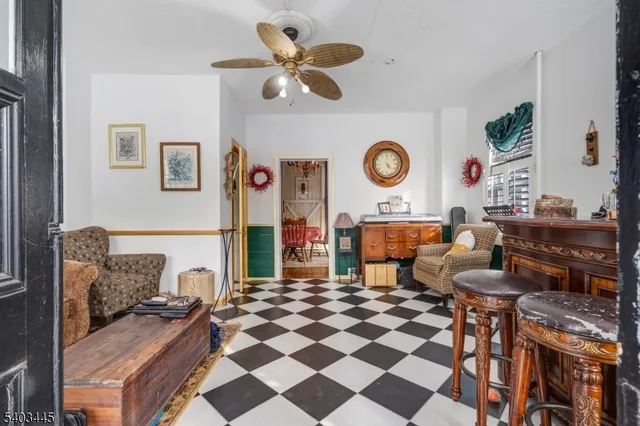 a living room with a black white checkered floor with couches chair and a stove with wooden floor