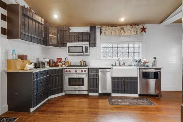 a kitchen with kitchen island granite countertop a sink cabinets and stainless steel appliances